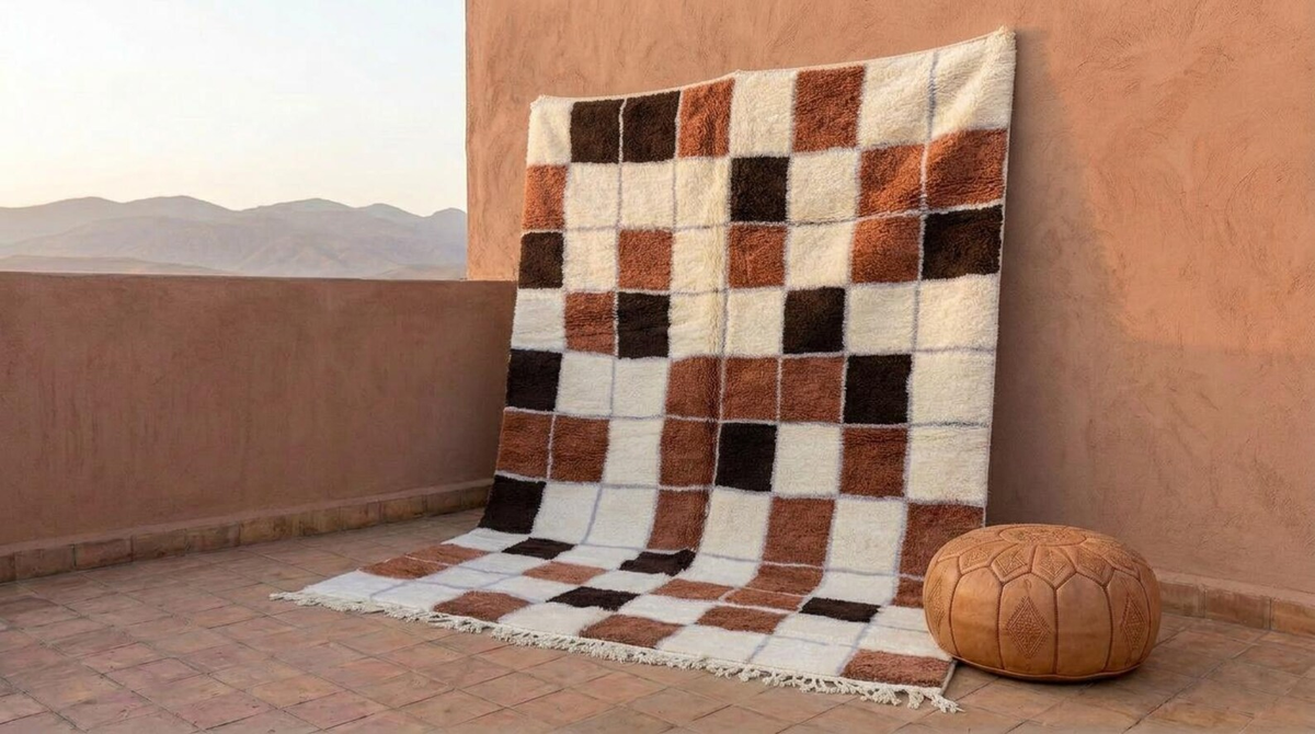 Ivory, caramel, and dark brown checkered rug with fringed edges displayed on a terrace.
